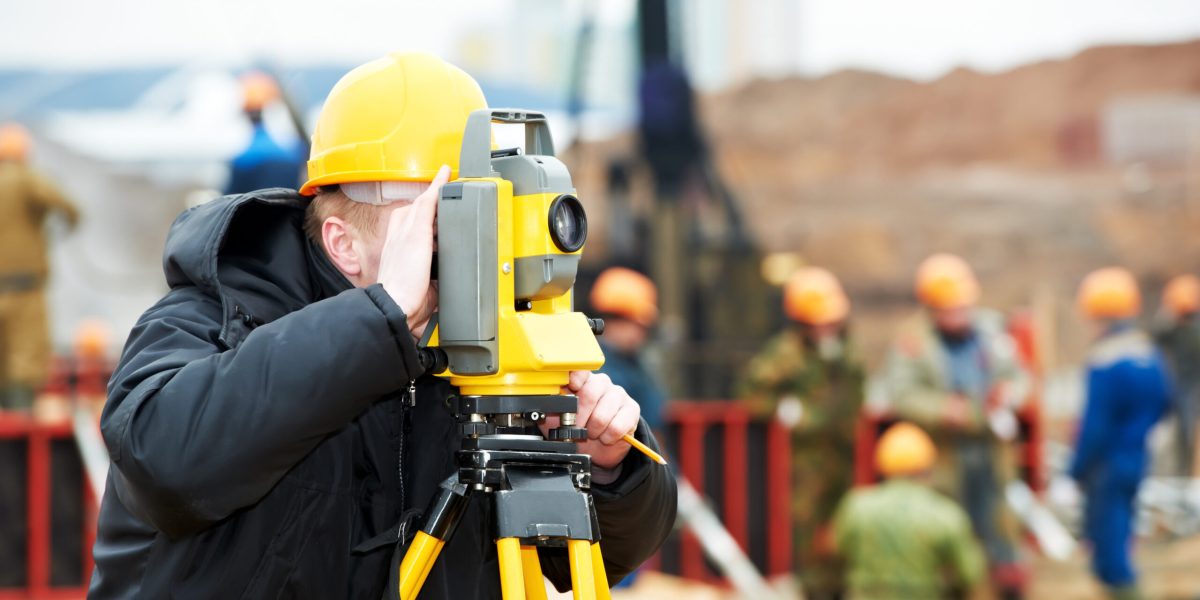 One surveyor worker working with theodolite transit equipment at construction site outdoors